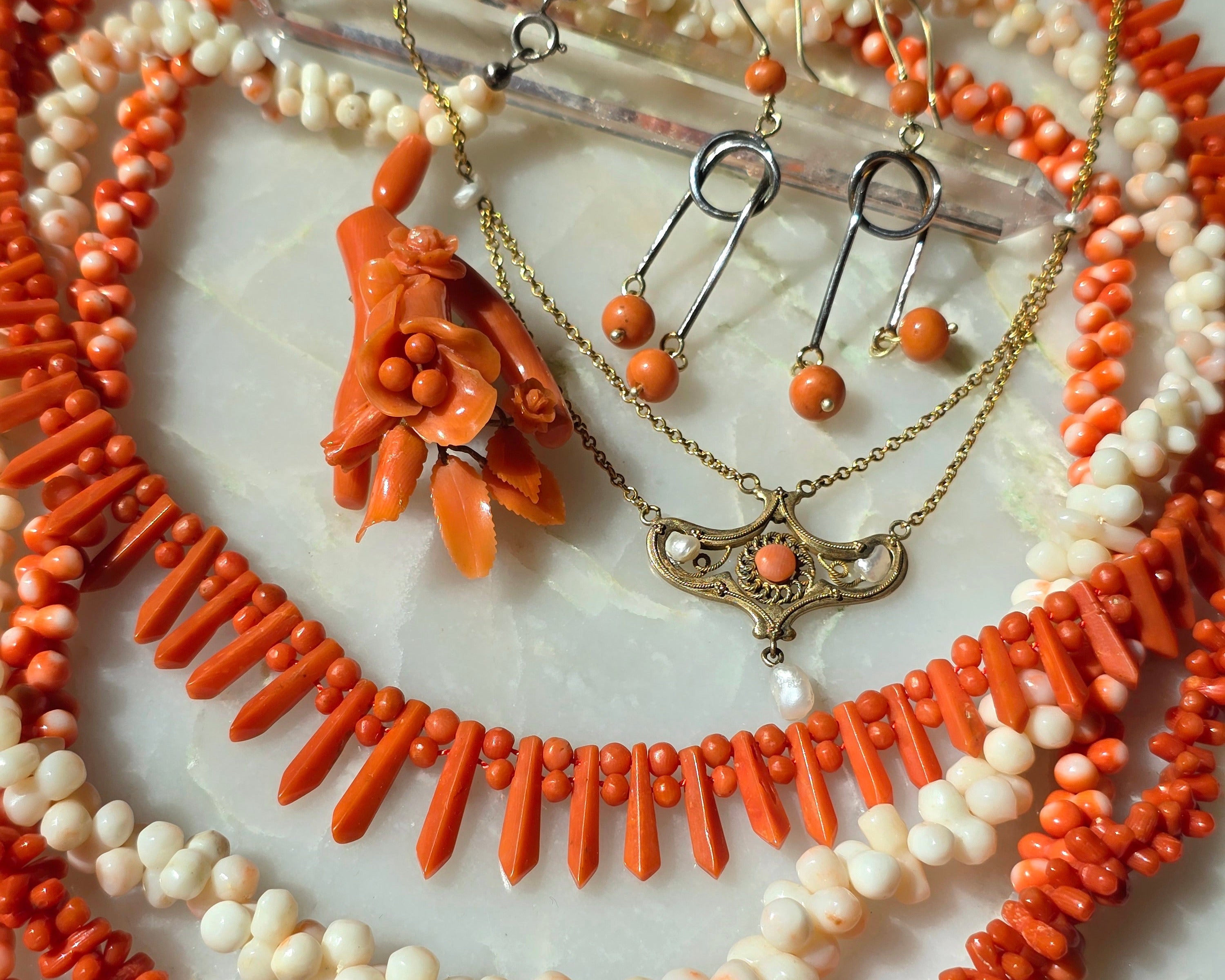 Collection of coral and pearl jewelry on a marble surface